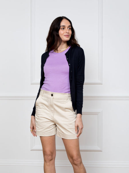 Woman wearing navy blue long sleeve cardigan knit in a luxury and premium sea island cotton. Paired with ultraviolet/lilac short sleeve knit top.